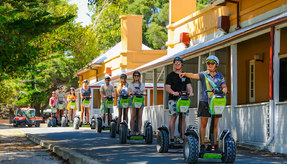 People on Segways during a tour on Rottnest Island, passing historic buildings.
