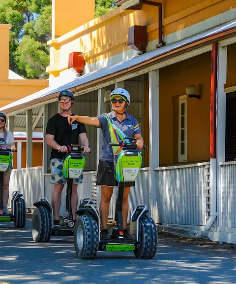 People on Segways during a tour on Rottnest Island, passing historic buildings.