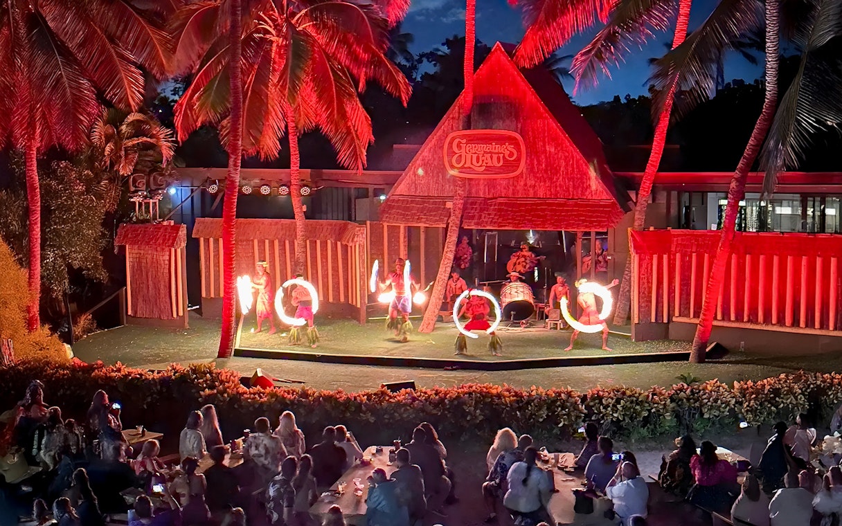 Fire dancers performing on stage at Germaine's Luau with audience watching.