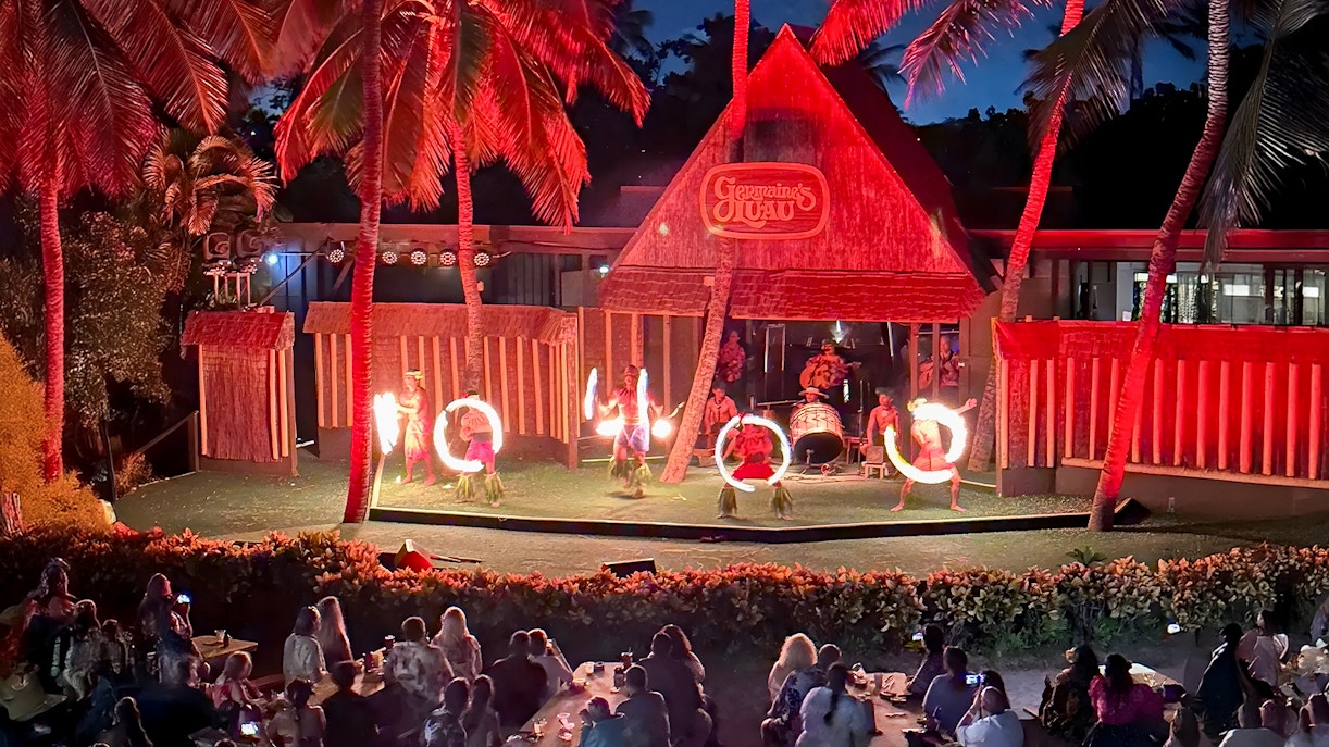 Fire dancers performing on stage at Germaine's Luau with audience watching.