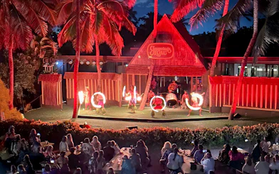 Fire dancers performing on stage at Germaine's Luau with audience watching.