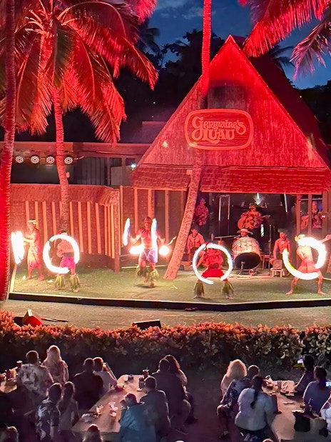 Fire dancers performing on stage at Germaine's Luau with audience watching.