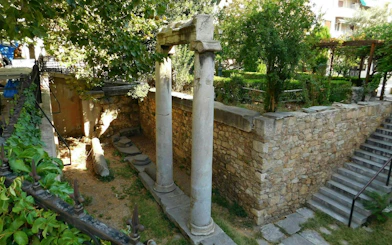 Ancient stone columns and ruins in Plaka, Athens, surrounded by greenery.