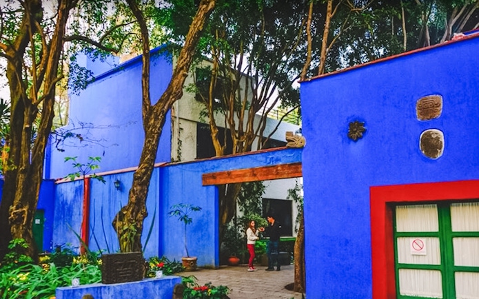 Frida Kahlo Museum courtyard with vibrant blue walls and lush greenery, Mexico City.