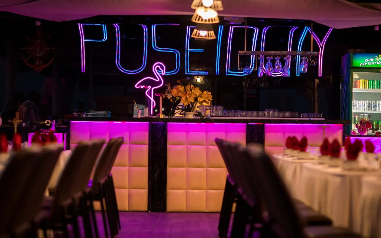 Neon-lit bar on Da Nang dinner cruise with tables set for guests.