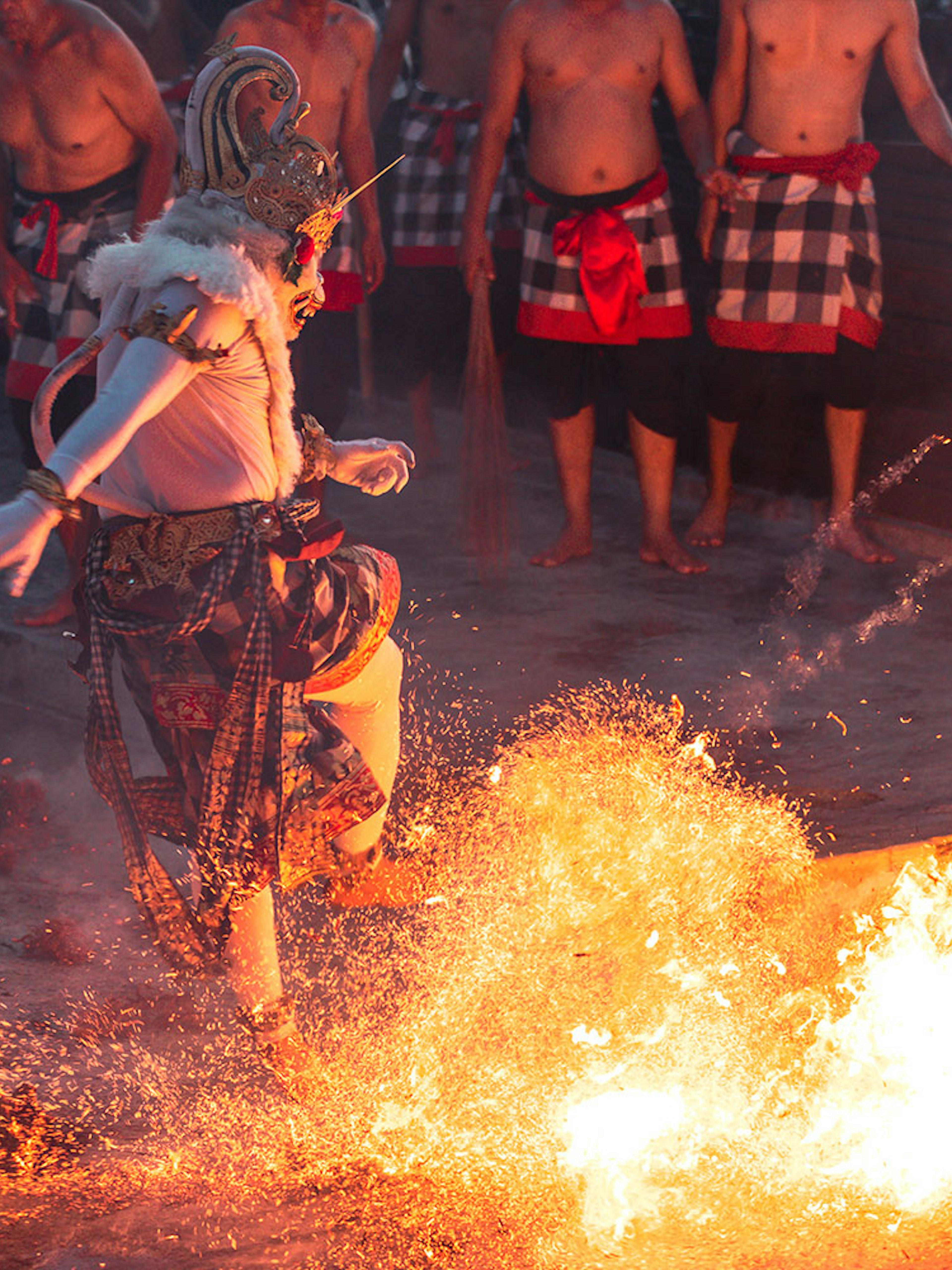 Performer in traditional costume dancing around fire at Ubud Kecak & Fire Dance Show.