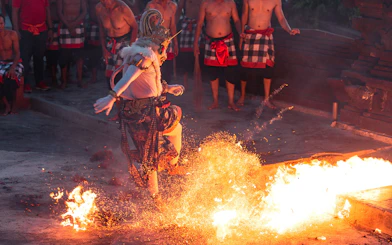 Performer in traditional costume dancing around fire at Ubud Kecak & Fire Dance Show.