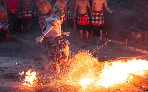 Performer in traditional costume dancing around fire at Ubud Kecak & Fire Dance Show.