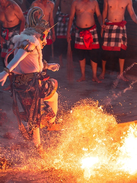 Performer in traditional costume dancing around fire at Ubud Kecak & Fire Dance Show.