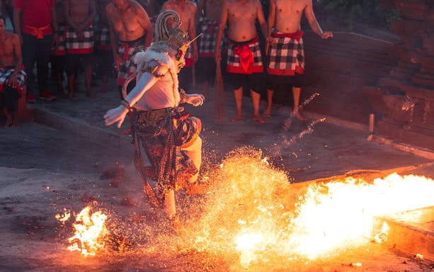 Performer in traditional costume dancing around fire at Ubud Kecak & Fire Dance Show.