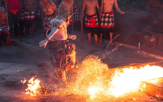 Performer in traditional costume dancing around fire at Ubud Kecak & Fire Dance Show.