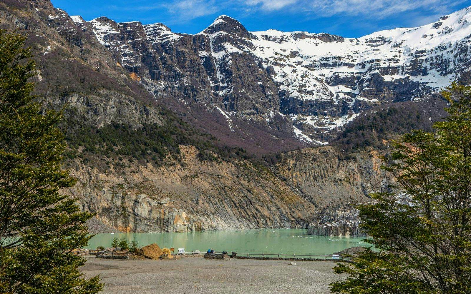 Mount Tronador and glacial lagoon near Pampa Linda, surrounded by rugged cliffs and snow-capped peaks.