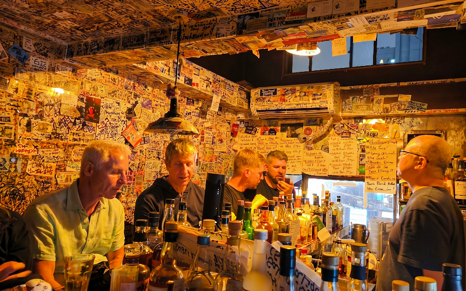 Shinjuku bar interior with patrons at a graffiti-covered counter in Tokyo.