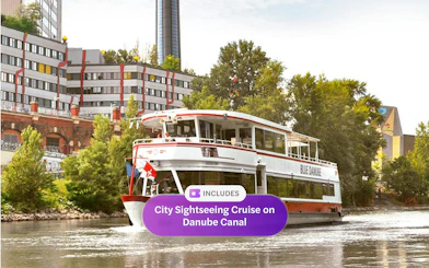 Sightseeing cruise boat on Danube Canal near Spittelau incinerator, Vienna.