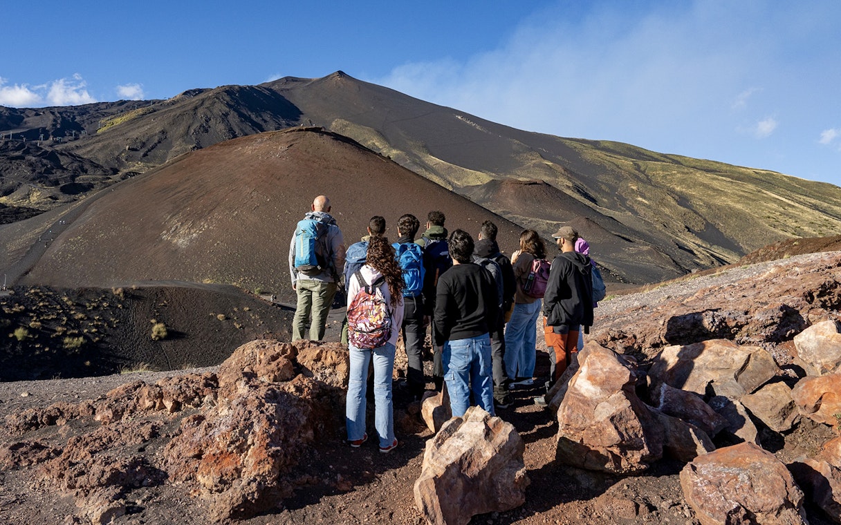 Group of tourists on a guided tour of Mount Etna's volcanic landscape in Catania.