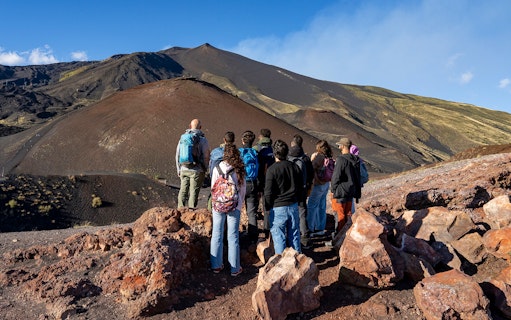 Group of tourists on a guided tour of Mount Etna's volcanic landscape in Catania.