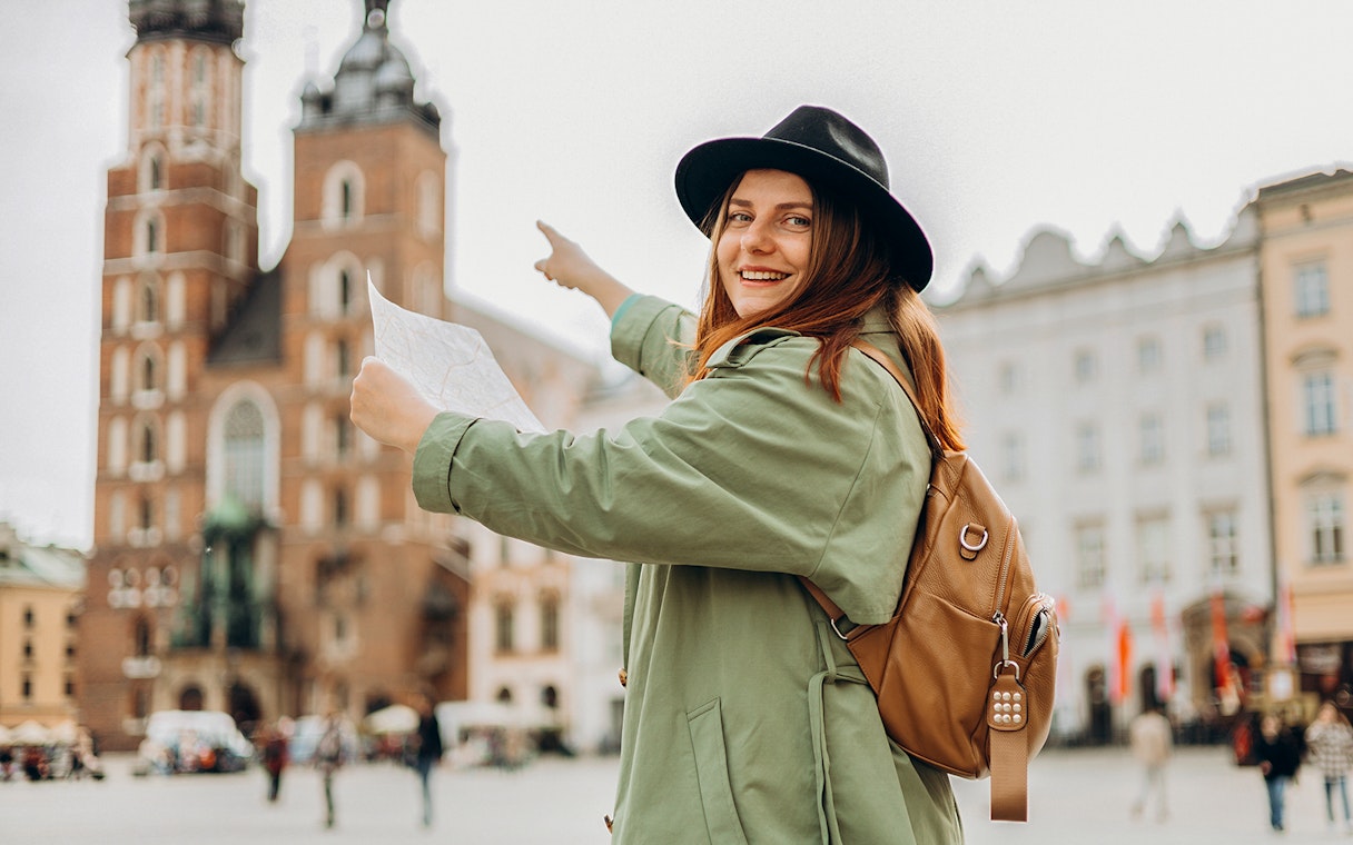 Traveler pointing at St. Mary’s Basilica in Krakow's Old Town during guided tour.