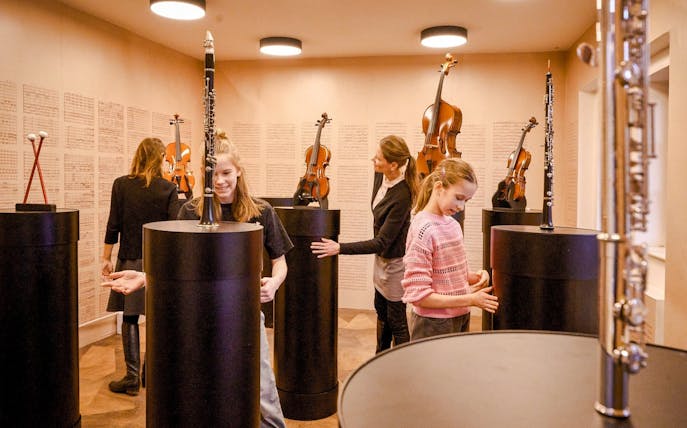 Guests exploring musical instruments at Mozart Interactive Museum, Prague.