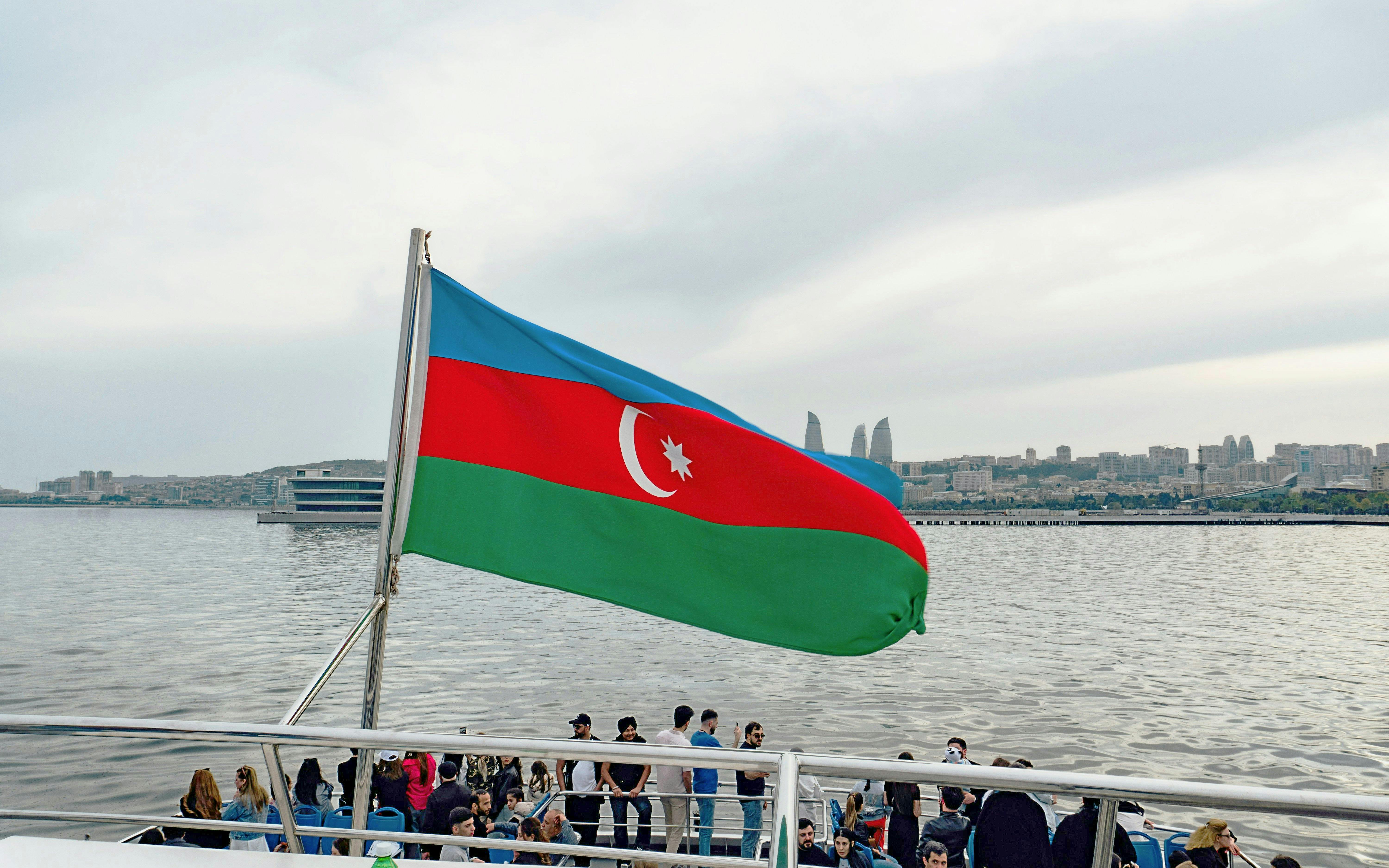 Boat tour in Baku with Azerbaijan flag and city skyline in the background.