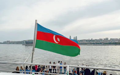 Boat tour in Baku with Azerbaijan flag and city skyline in the background.