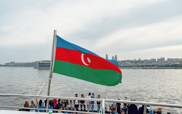 Boat tour in Baku with Azerbaijan flag and city skyline in the background.