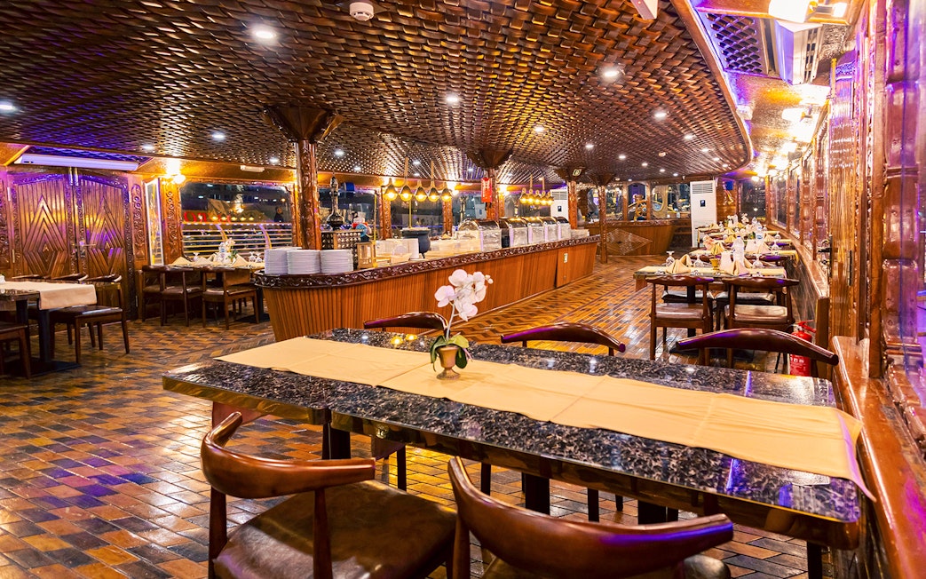 Elegant dining setup on Alexandra Dhow Cruise, Dubai Marina, with buffet and ambient lighting.