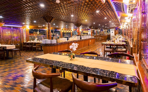 Elegant dining setup on Alexandra Dhow Cruise, Dubai Marina, with buffet and ambient lighting.