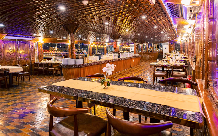 Elegant dining setup on Alexandra Dhow Cruise, Dubai Marina, with buffet and ambient lighting.