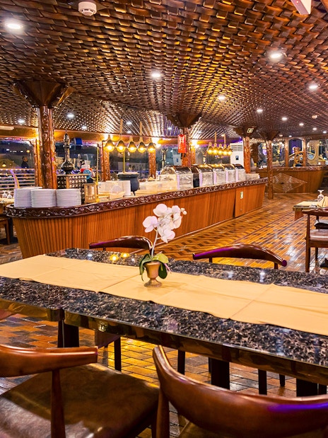 Elegant dining setup on Alexandra Dhow Cruise, Dubai Marina, with buffet and ambient lighting.