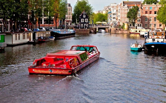 City Sightseeing Amsterdam boat cruising through canal with historic buildings.