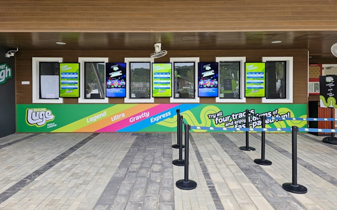 Ticket counter at Skyline Luge Kuala Lumpur with colorful signage and track options.