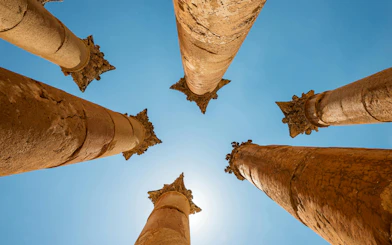 Roman columns of the Temple of Artemis in Jerash, Jordan, viewed from below against blue sky.