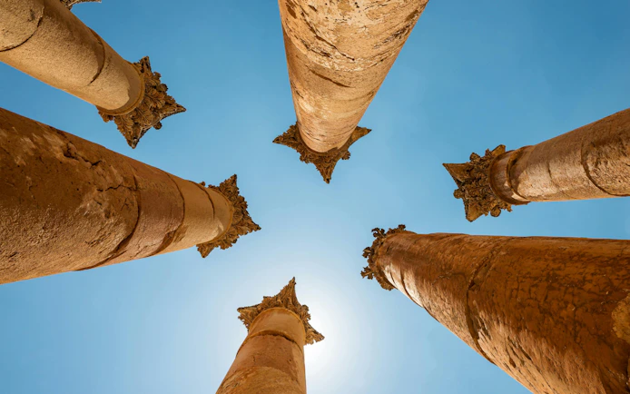 Roman columns of the Temple of Artemis in Jerash, Jordan, viewed from below against blue sky.
