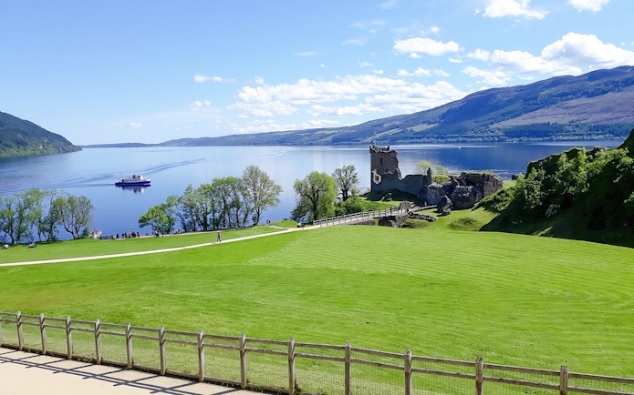 Urquhart Castle ruins by Loch Ness with a boat on the water.