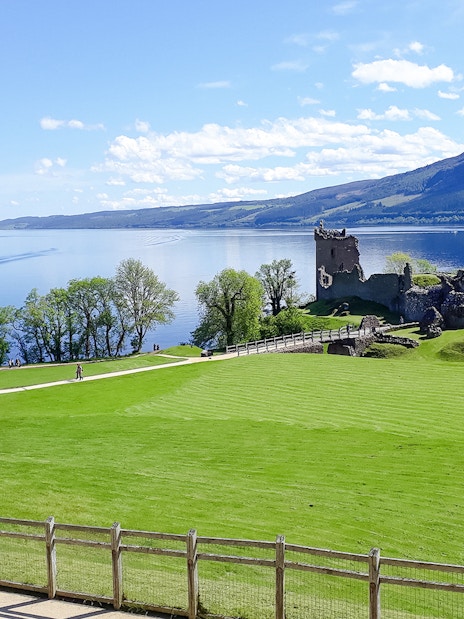 Urquhart Castle ruins by Loch Ness with a boat on the water.
