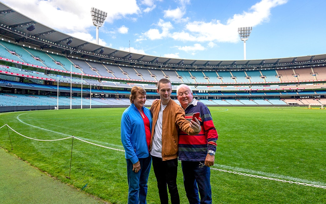 Visitors taking a selfie on the field during a tour of the Melbourne Cricket Ground.