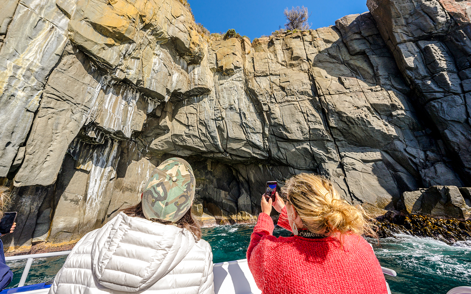 Visitors photographing sea cliffs on Cape Raoul cruise, Tasmania.