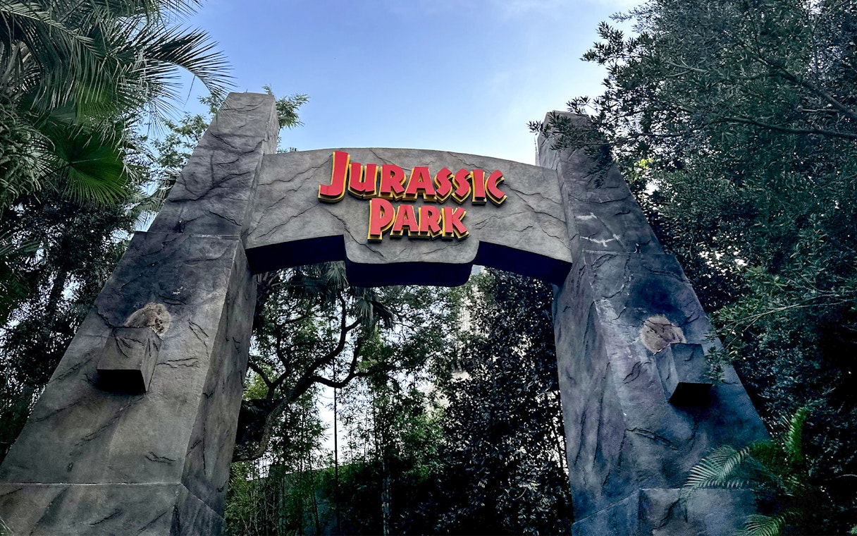 Jurassic Park entrance arch at Universal Orlando, Florida surrounded by lush greenery.