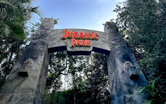 Jurassic Park entrance arch at Universal Orlando, Florida surrounded by lush greenery.