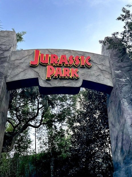 Jurassic Park entrance arch at Universal Orlando, Florida surrounded by lush greenery.