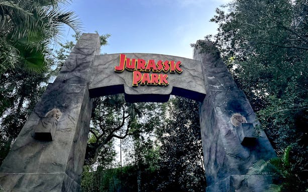 Jurassic Park entrance arch at Universal Orlando, Florida surrounded by lush greenery.