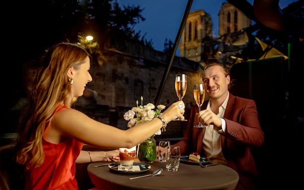Couple toasting with champagne on a Seine River cruise in Paris.
