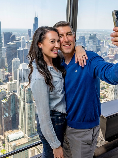 Couple taking a selfie at Chicago 360 Observation Deck with city skyline view.