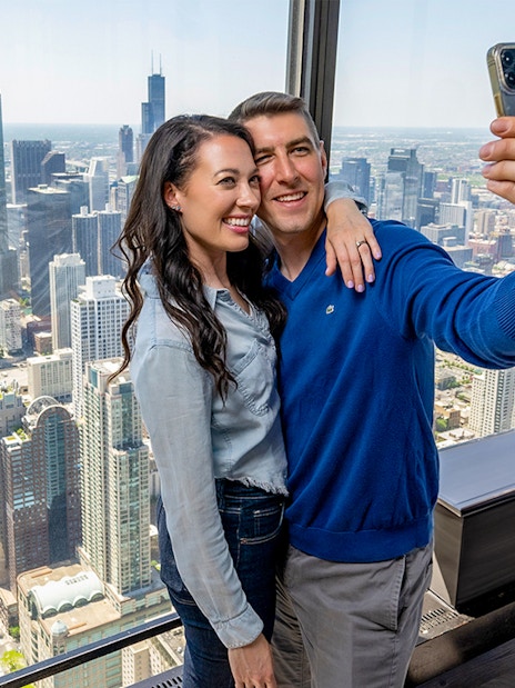 Couple taking a selfie at Chicago 360 Observation Deck with city skyline view.