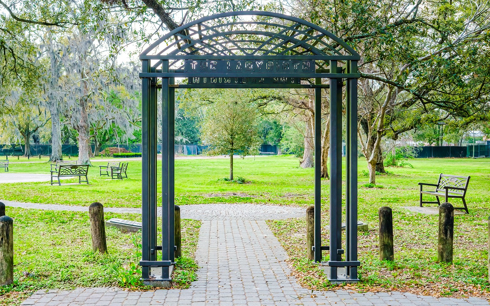 Hurricane Katrina memorial archway in Audubon Park, New Orleans, surrounded by trees and benches.