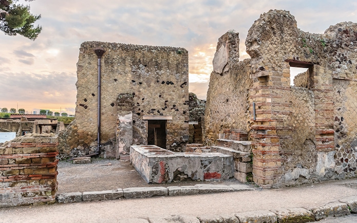 Ancient thermopolium ruins in Herculaneum with stone counters and walls.