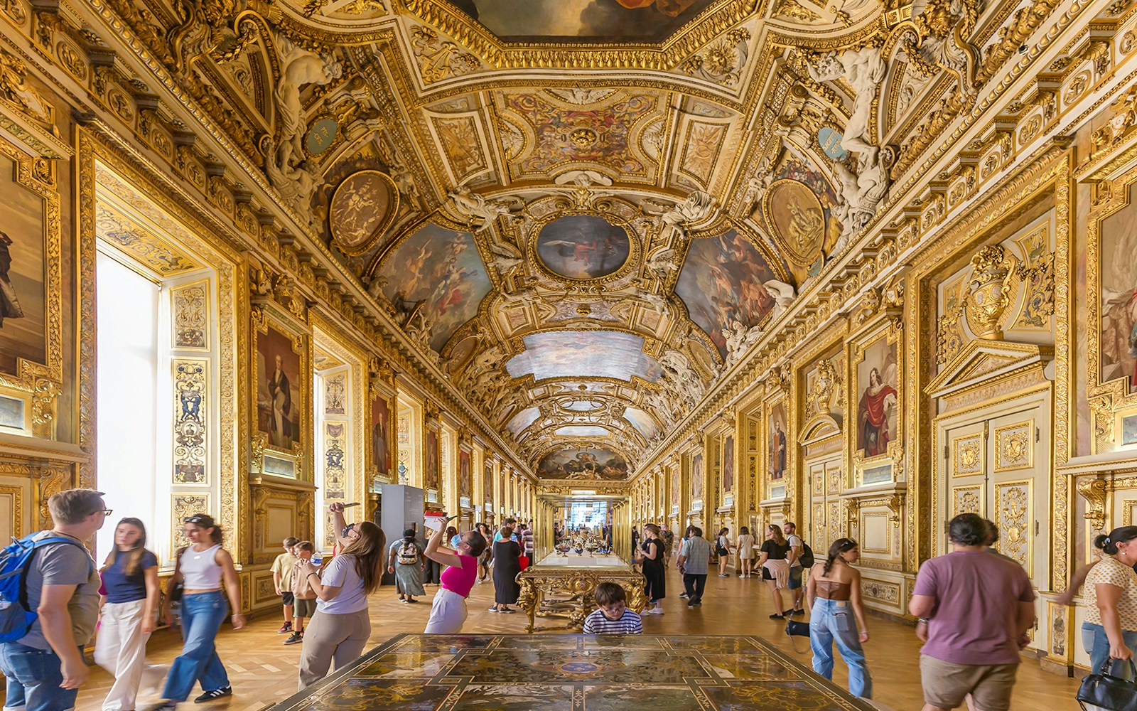 Tourists exploring the iconic Louvre Museum in Paris, featuring the glass pyramid entrance