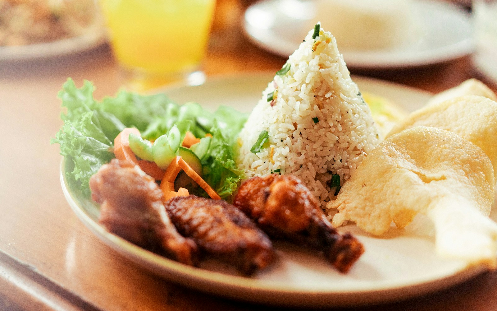 Nasi goreng with chicken, vegetables, and crackers served at a restaurant.