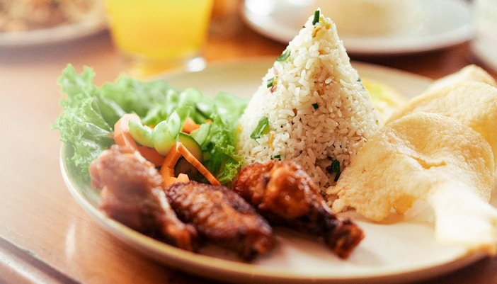 Nasi goreng with chicken, vegetables, and crackers served at a restaurant.