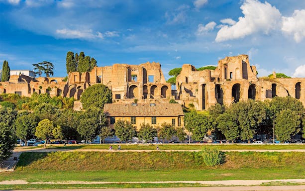 Ancient ruins on Palatine Hill in Rome with trees and a clear sky.
